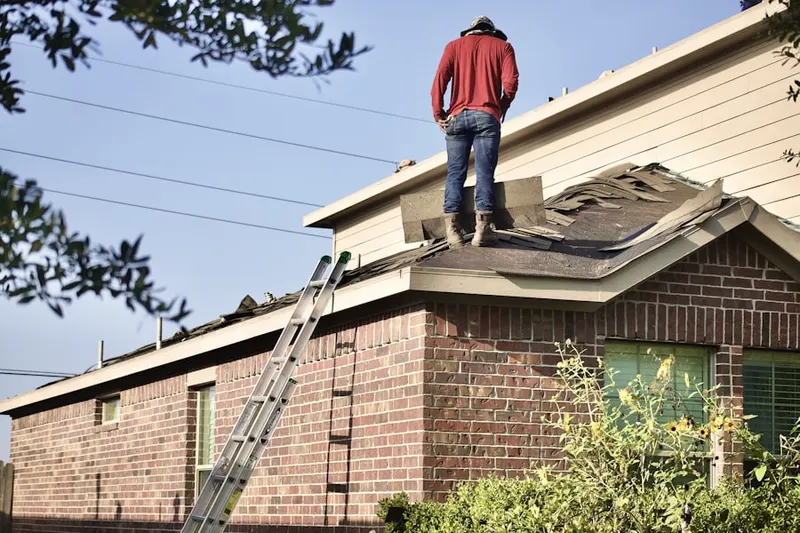 Professional roofer working on a residential roof in Genola